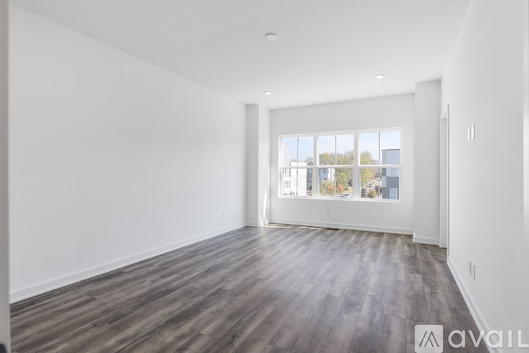 A spacious room with wooden flooring and a large window.