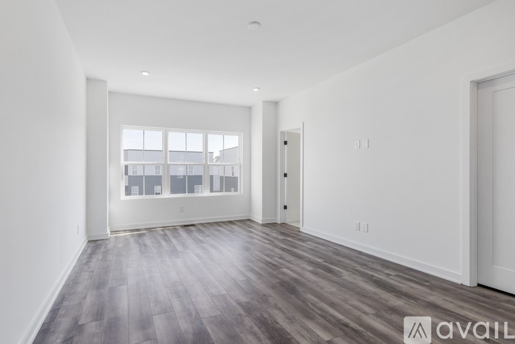 A spacious room with wooden flooring and white walls.