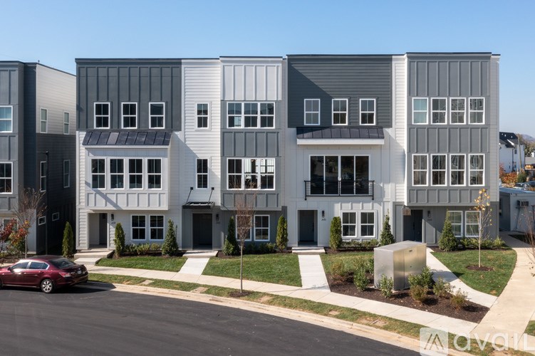 A row of modern townhouses with a red car parked in front of the first one.