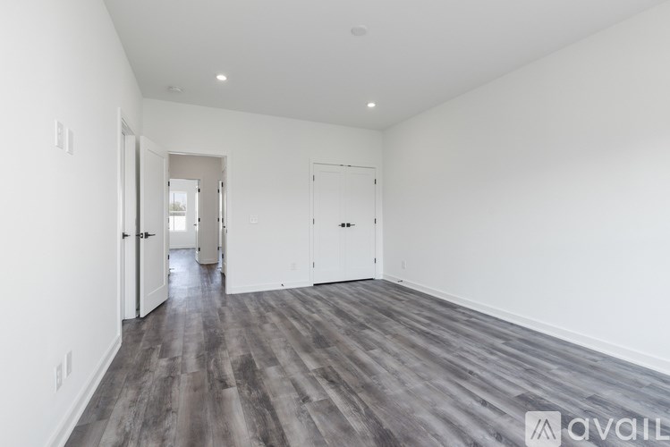 A spacious room with wood flooring and white walls.