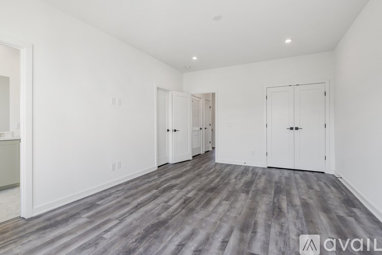 A spacious room with wood flooring and white walls.