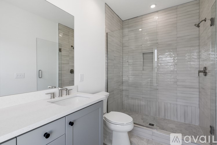 A bathroom with a white toilet, sink, and tiled shower.