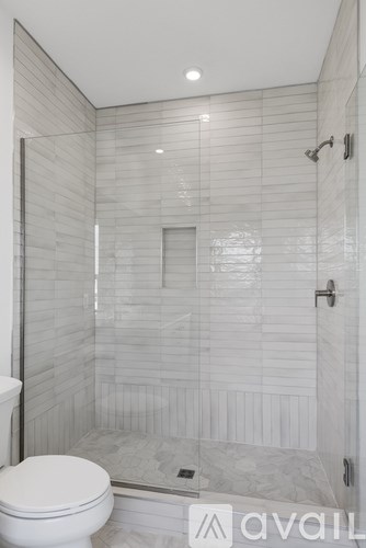 A white toilet is in a tiled bathroom with a walk-in shower.