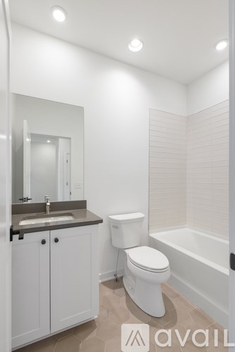 A white toilet is in a bathroom with a sink and mirror.