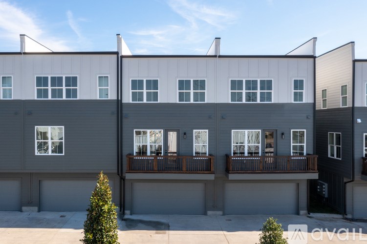 A modern building with a balcony and a tree in front.