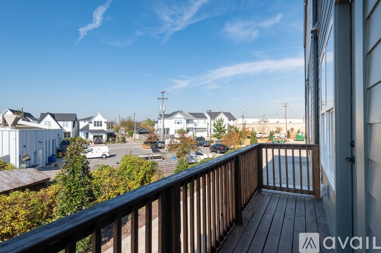 A balcony overlooks a residential area with houses and cars.