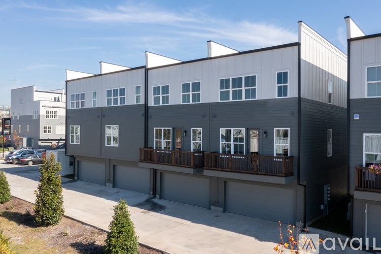 A row of modern townhouses with balconies and a clear blue sky.