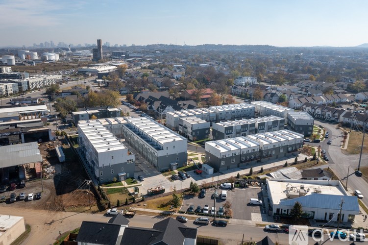 A large industrial area with multiple buildings and a city skyline in the distance.
