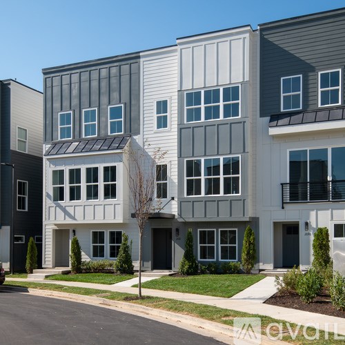A row of modern townhouses with balconies and landscaped front yards.