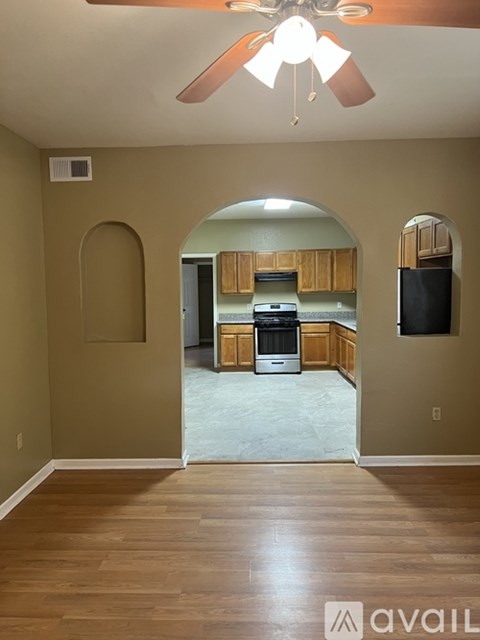 A kitchen with a fan on the ceiling and a refrigerator on the wall.