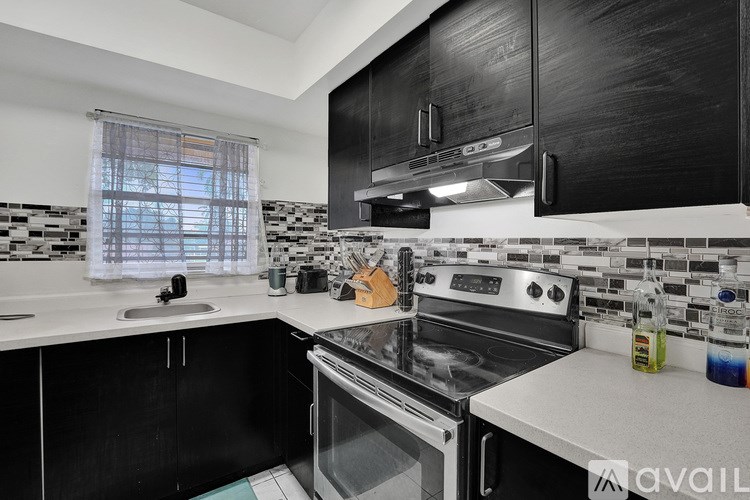 A modern kitchen with black cabinets and a stainless steel oven.