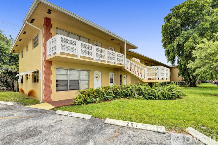 A yellow house with a balcony and a driveway in front.