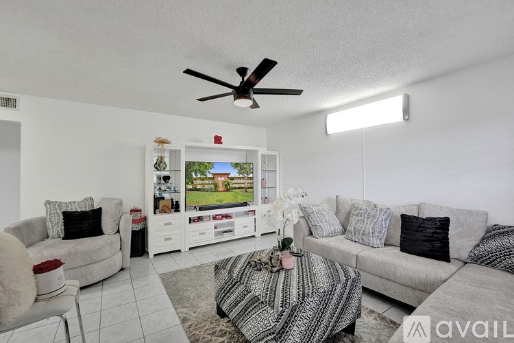 A living room with a grey couch, a white chair, a coffee table, and a ceiling fan.