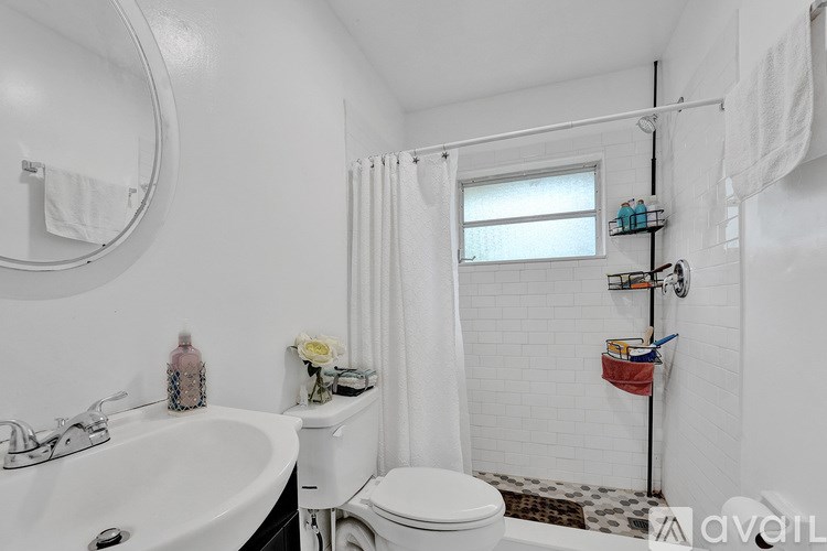 A white bathroom with a toilet, sink, and shower.