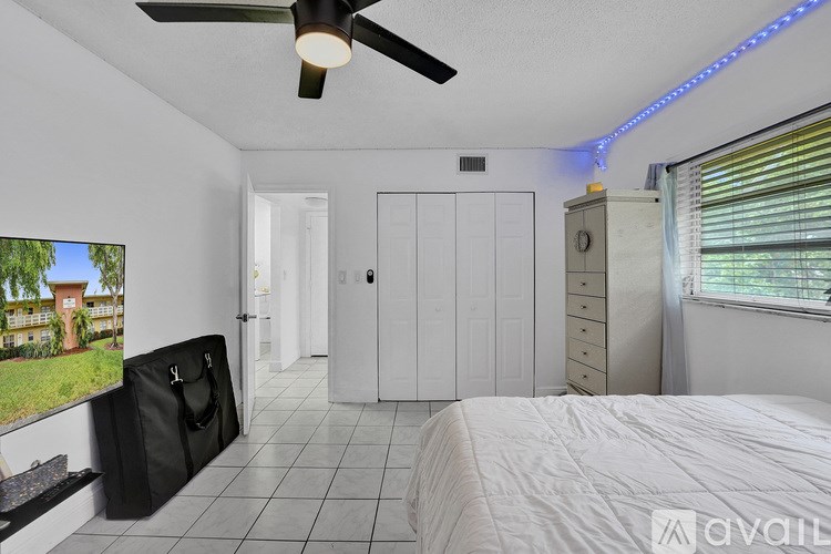 A bedroom with a bed, dresser, and a ceiling fan with a light.