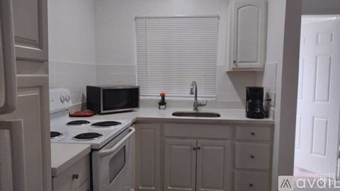 A kitchen with white appliances and cabinets.