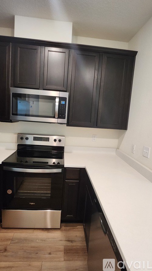 A kitchen with black cabinets and a stainless steel oven.
