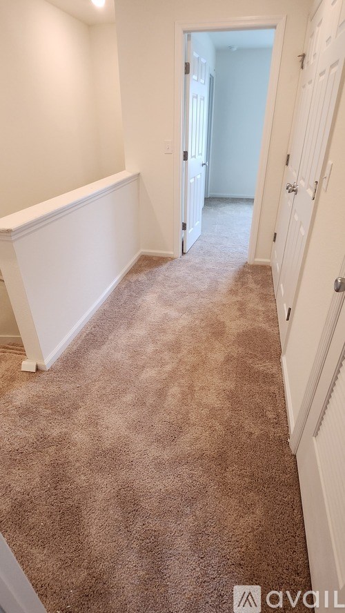 A hallway with carpeted flooring and white walls.