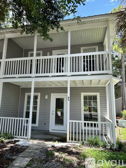A two-story house with a white porch and grey siding.