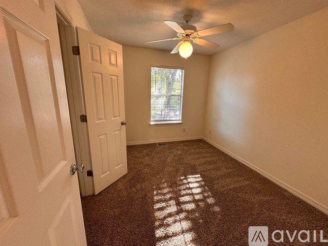 A white door with a silver handle is open to a hallway with a white wall and a white shelving unit.