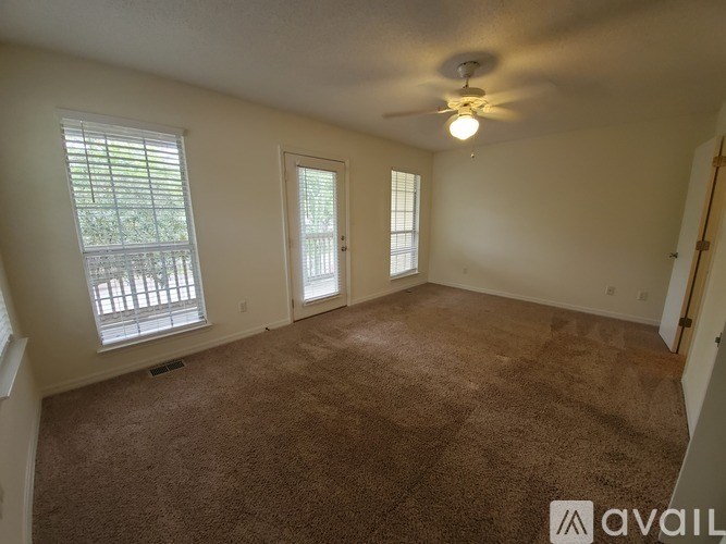 A room with a carpeted floor and a ceiling fan.