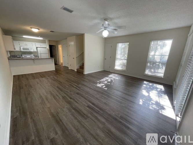 A spacious room with wood flooring and a ceiling fan.