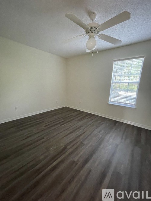 A room with a ceiling fan and wooden flooring.