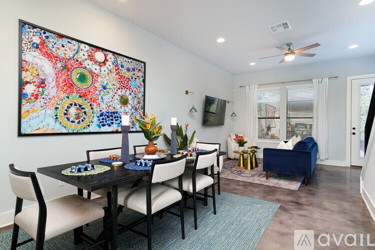 A dining room with a large painting on the wall and a blue couch in the background.