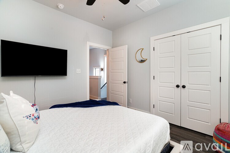 A bedroom with a bed, a television, and a ceiling fan.
