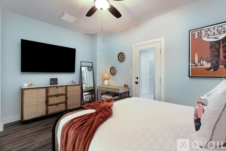 A bedroom with a bed, a dresser, a mirror, a ceiling fan, and a wall hanging.