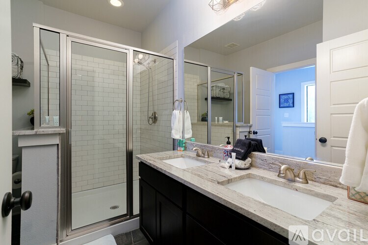 A bathroom with a sink, mirror, and shower.