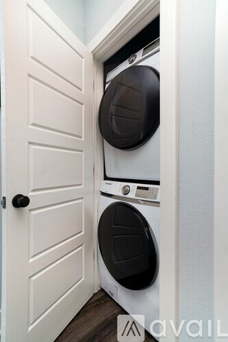 A white door is open to a small laundry room with a washer and dryer.