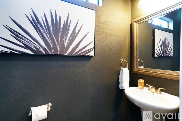 A bathroom with a sink, mirror, and a painting of a plant.