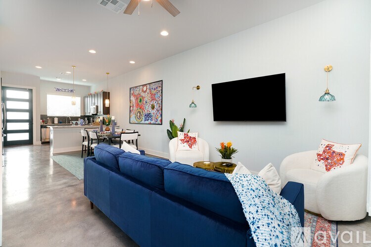 A living room with a blue couch and a television on the wall.