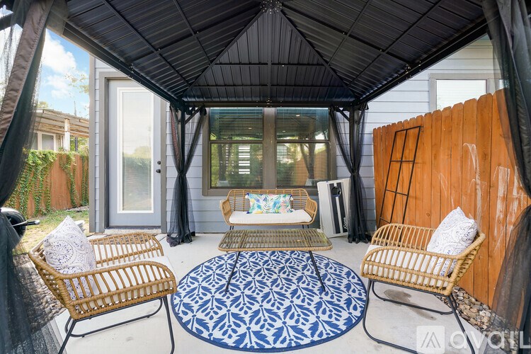 A patio with a wicker chair and a round rug.
