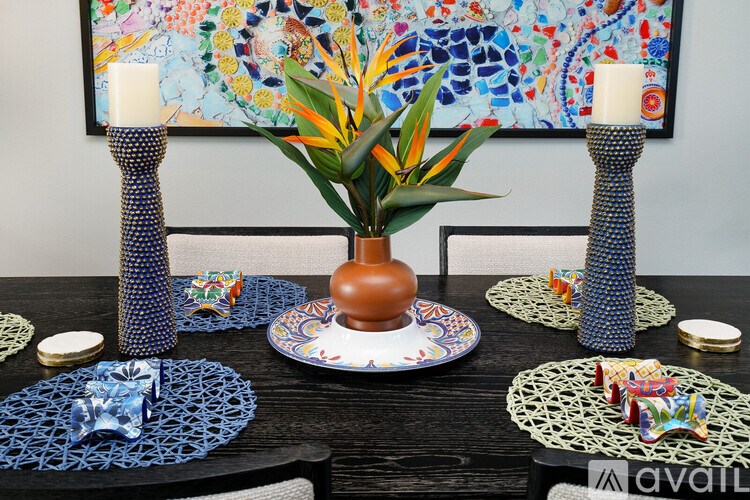 A table set with blue and white plates, a vase with a green plant, and two candles.
