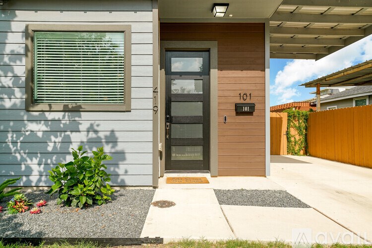 A modern house with a grey front door and a number 101 on the wall.