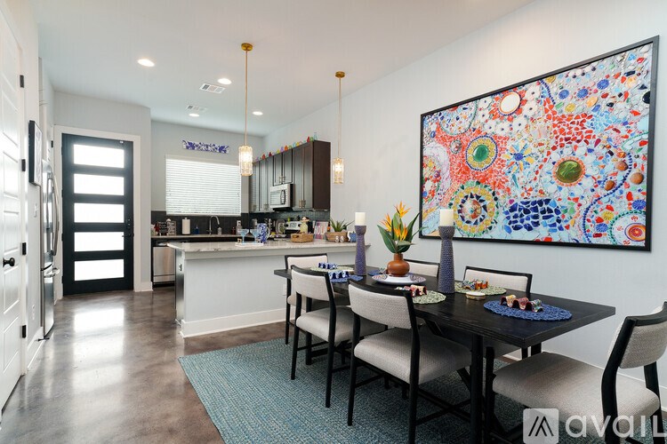 A dining room with a table set for four and a large painting on the wall.