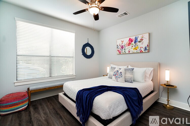 A bedroom with a bed, a ceiling fan, and a window with blinds.