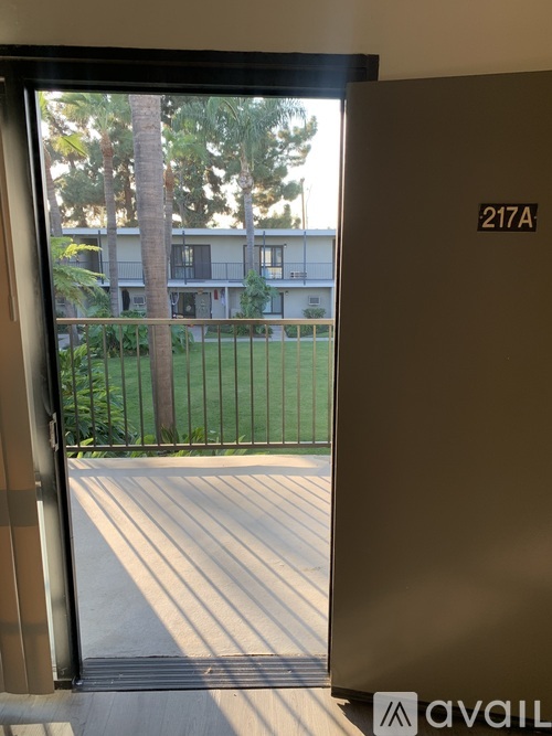 A view from inside a building looking out to a balcony with a fence and trees.