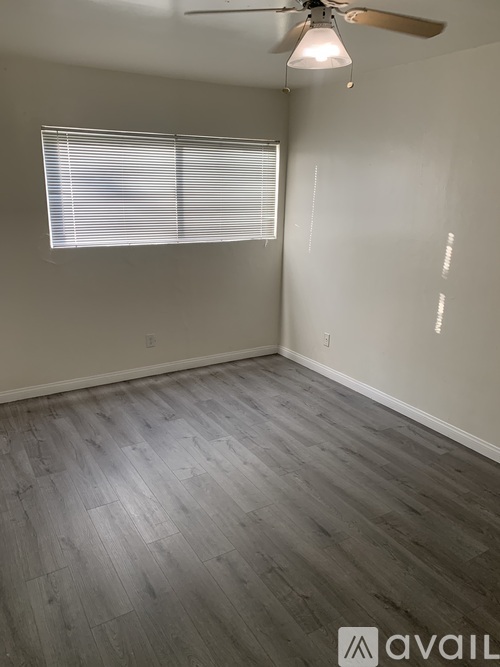 A room with a ceiling fan and a window with blinds.