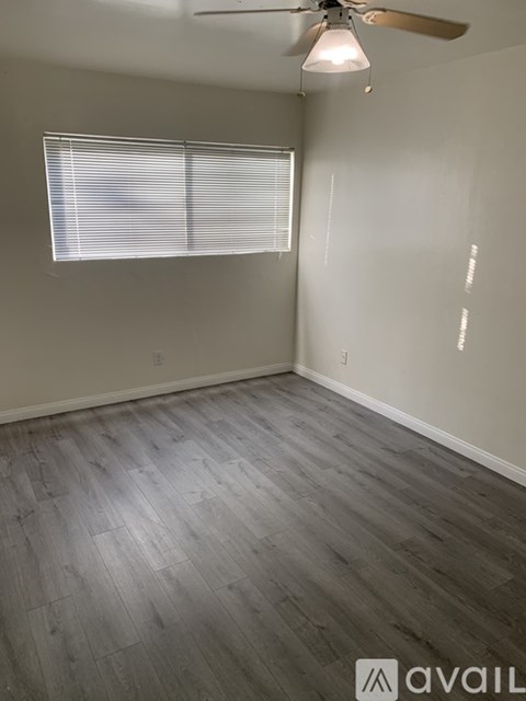 A room with a ceiling fan and a window with blinds.