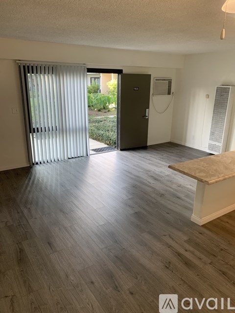 A room with a wooden floor and a sliding glass door leading outside.
