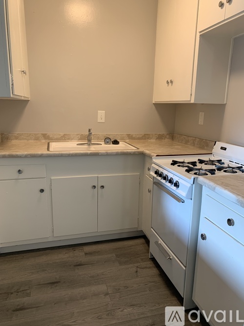A kitchen with white cabinets and a white stove.