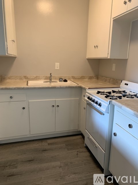 A kitchen with white cabinets and a white stove.