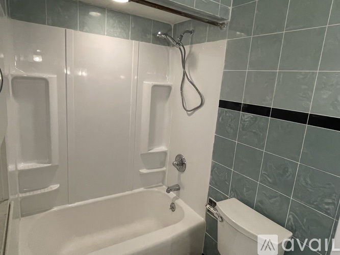 A white bathtub with a shower head and a toilet in a bathroom.