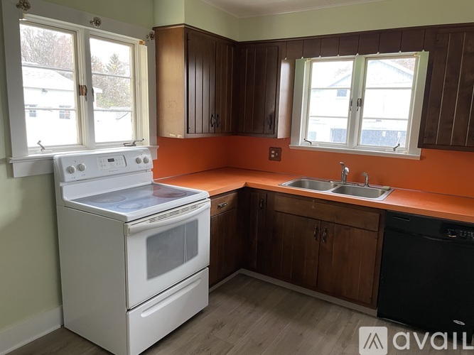 A kitchen with a white stove top oven and a black dishwasher.