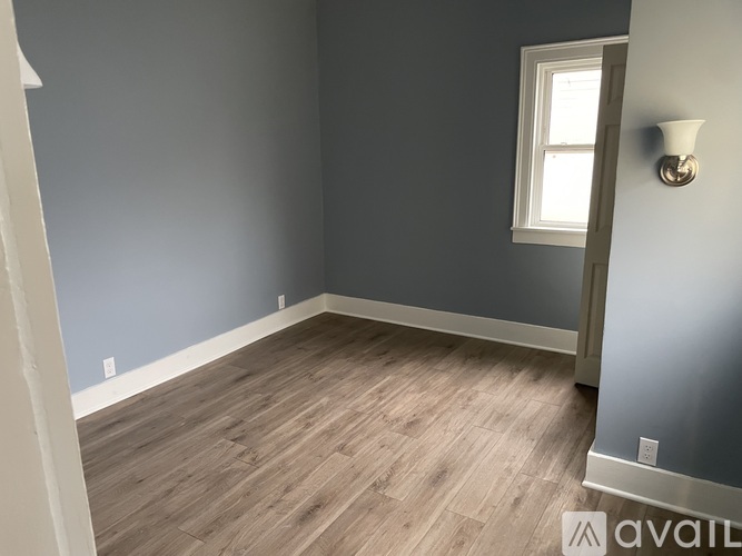 A room with wooden flooring and a window.