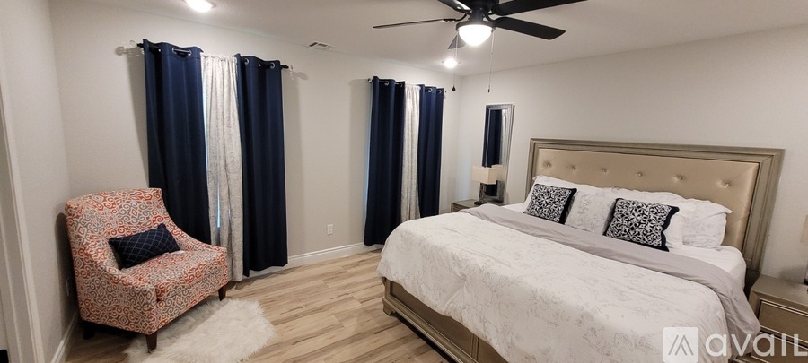 A bedroom with a large bed and a chair with a floral pattern.