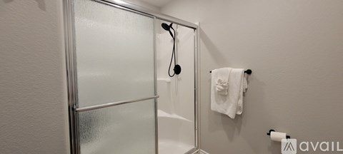 A white towel hangs on a towel rack in a bathroom.
